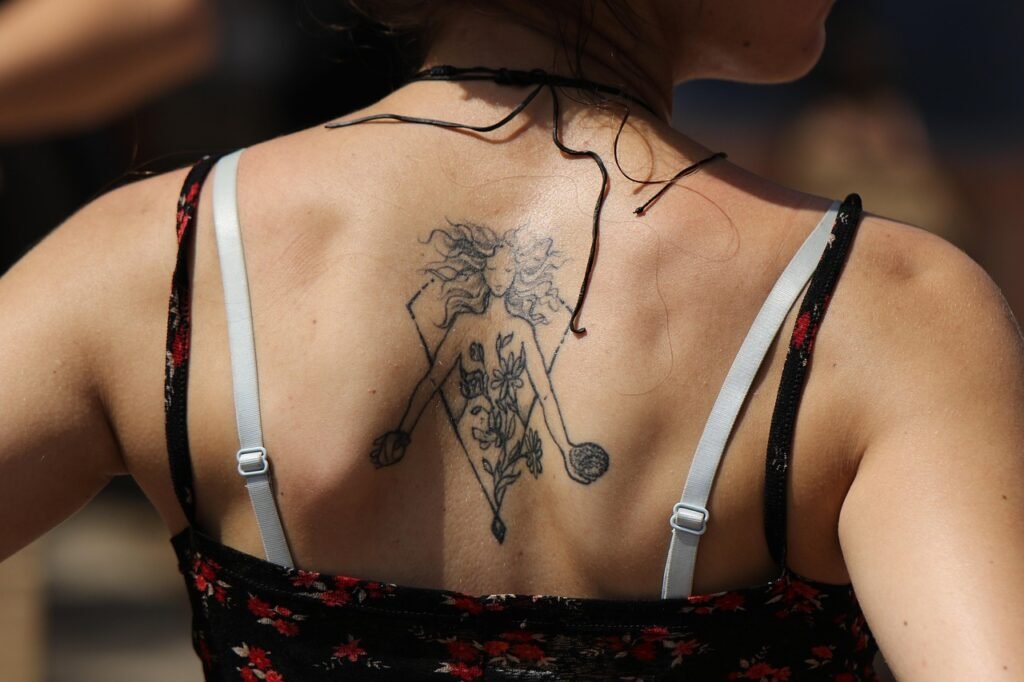 Girls with tattoo on on her back. Exploring tattoo styles.
